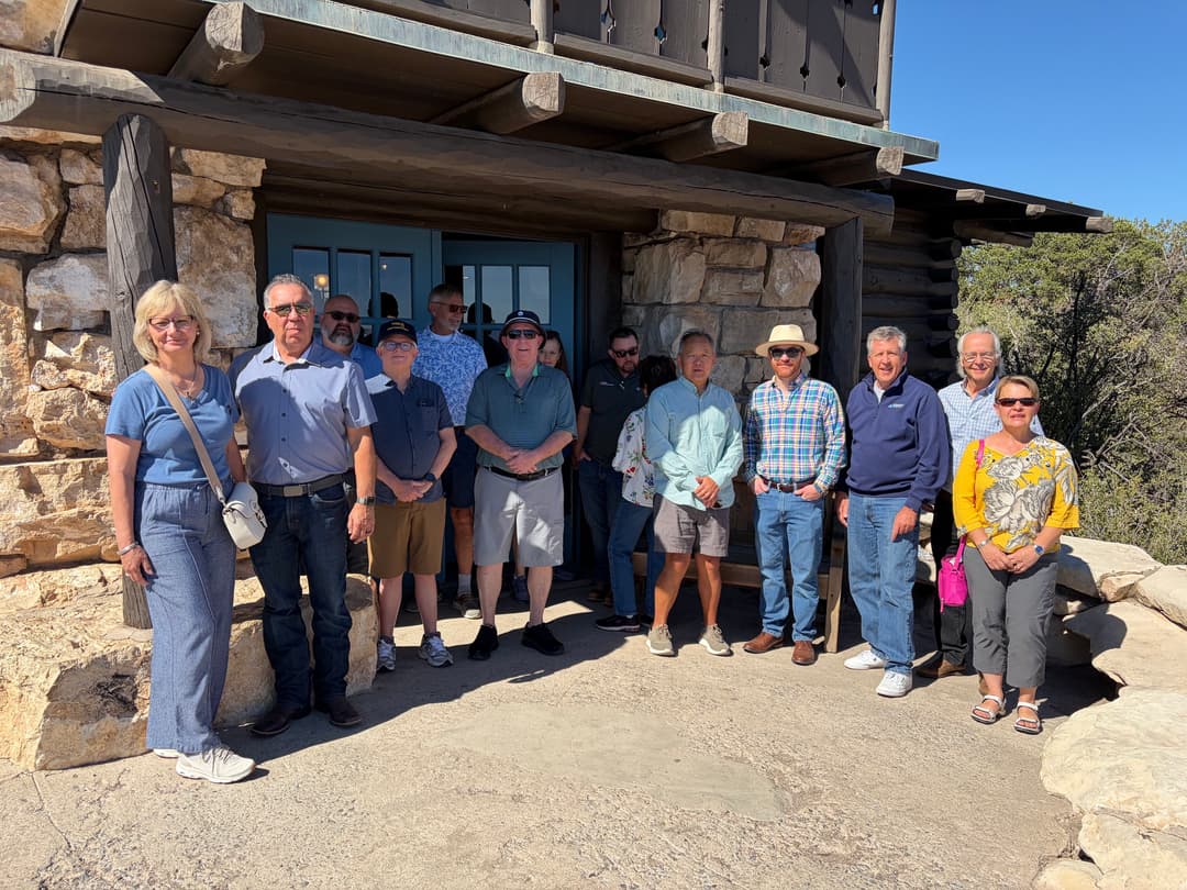 The tour group posed together outside the stone entrance of Lookout Studio under a clear sky.